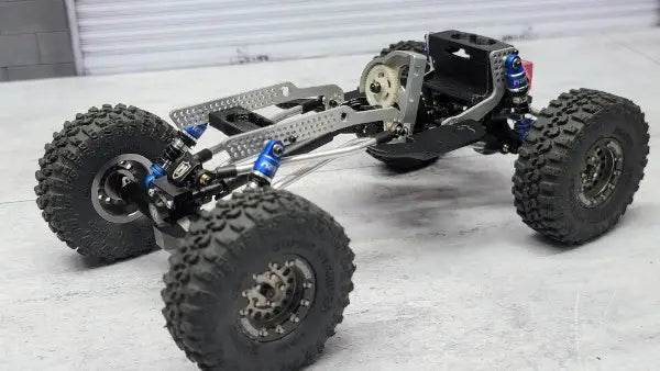 Aluminum RC crawler chassis with blue shocks and titanium links, designed by RCSTEVE for strength, balance, and competitive crawling.
