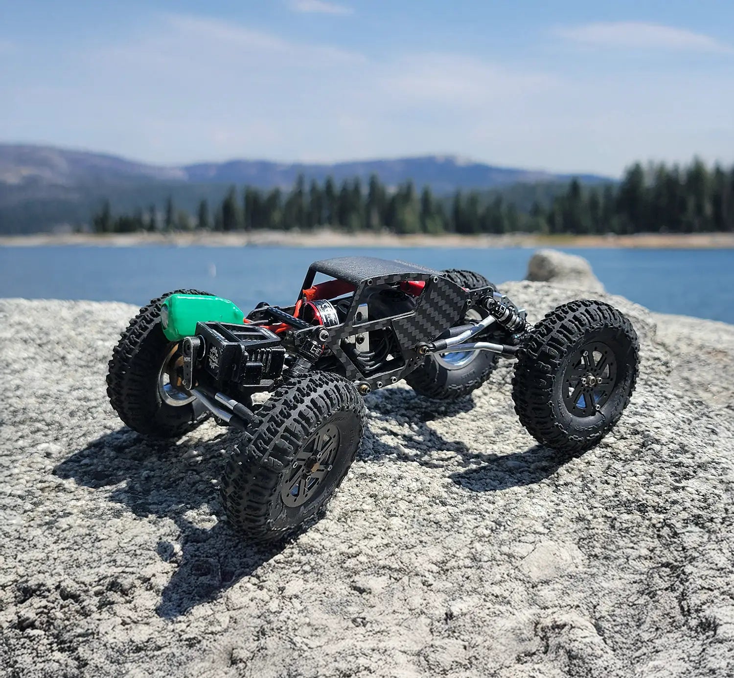 SEO Alt Text: RC crawler with carbon fiber frame and titanium links on rocky terrain by a lake, showcasing RCSTEVE off-road durability and design.