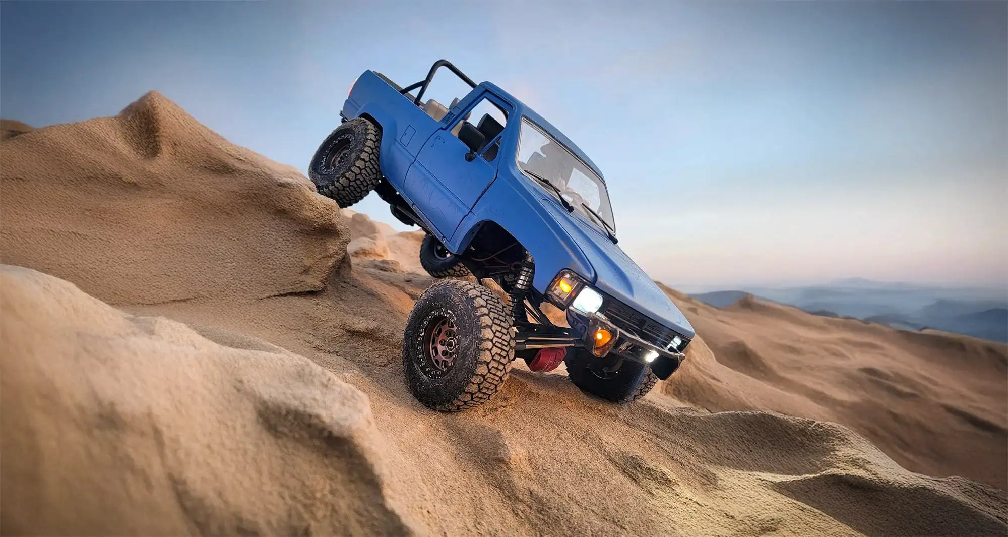 Blue RC crawler climbing steep rocky terrain at sunset, showcasing RCSTEVE performance upgrades built for power, traction, and control beyond limits.