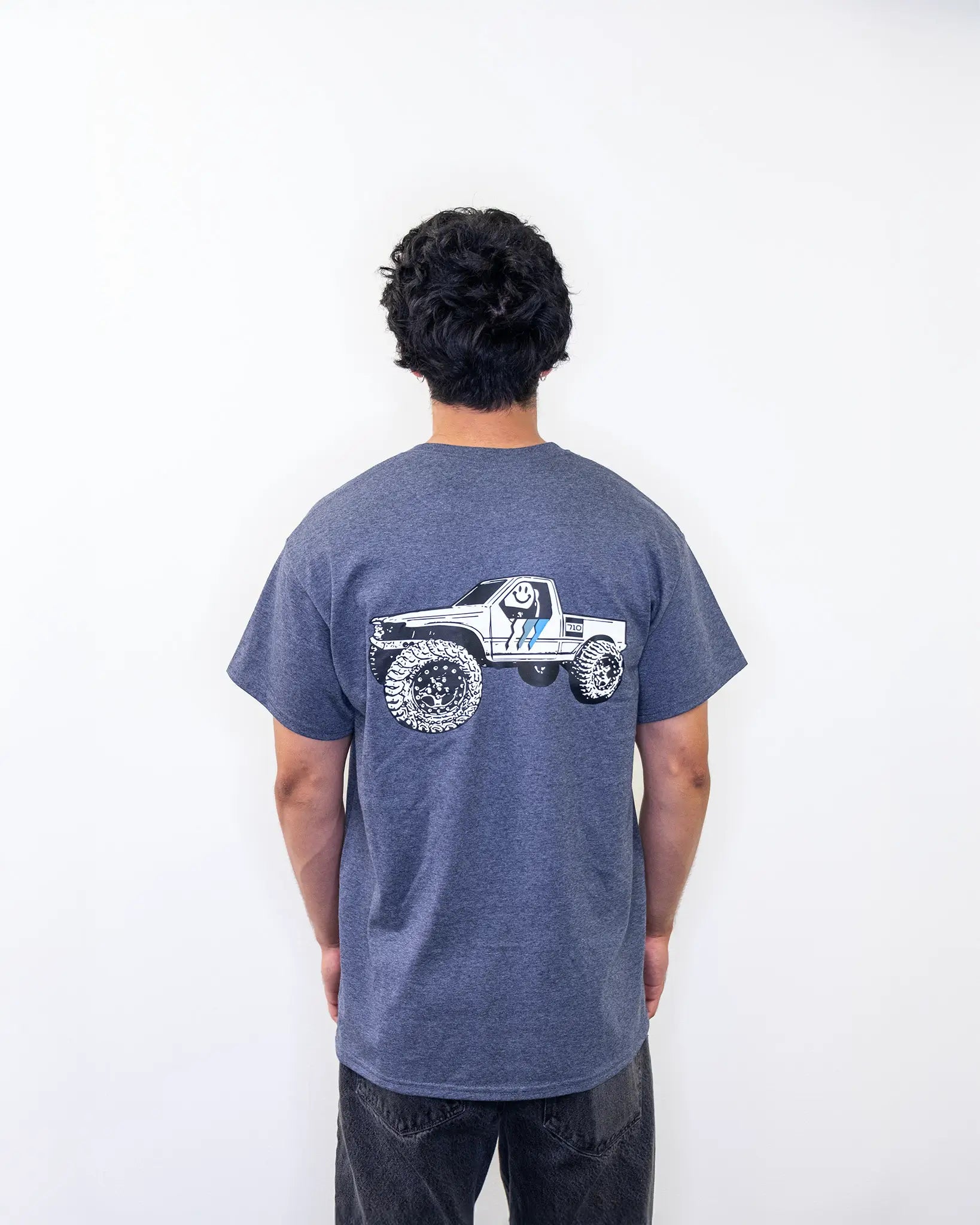 Back view of RCSTEVE 710 t-shirt showing a white RC truck graphic with off-road tires and the signature blue stripe logo.