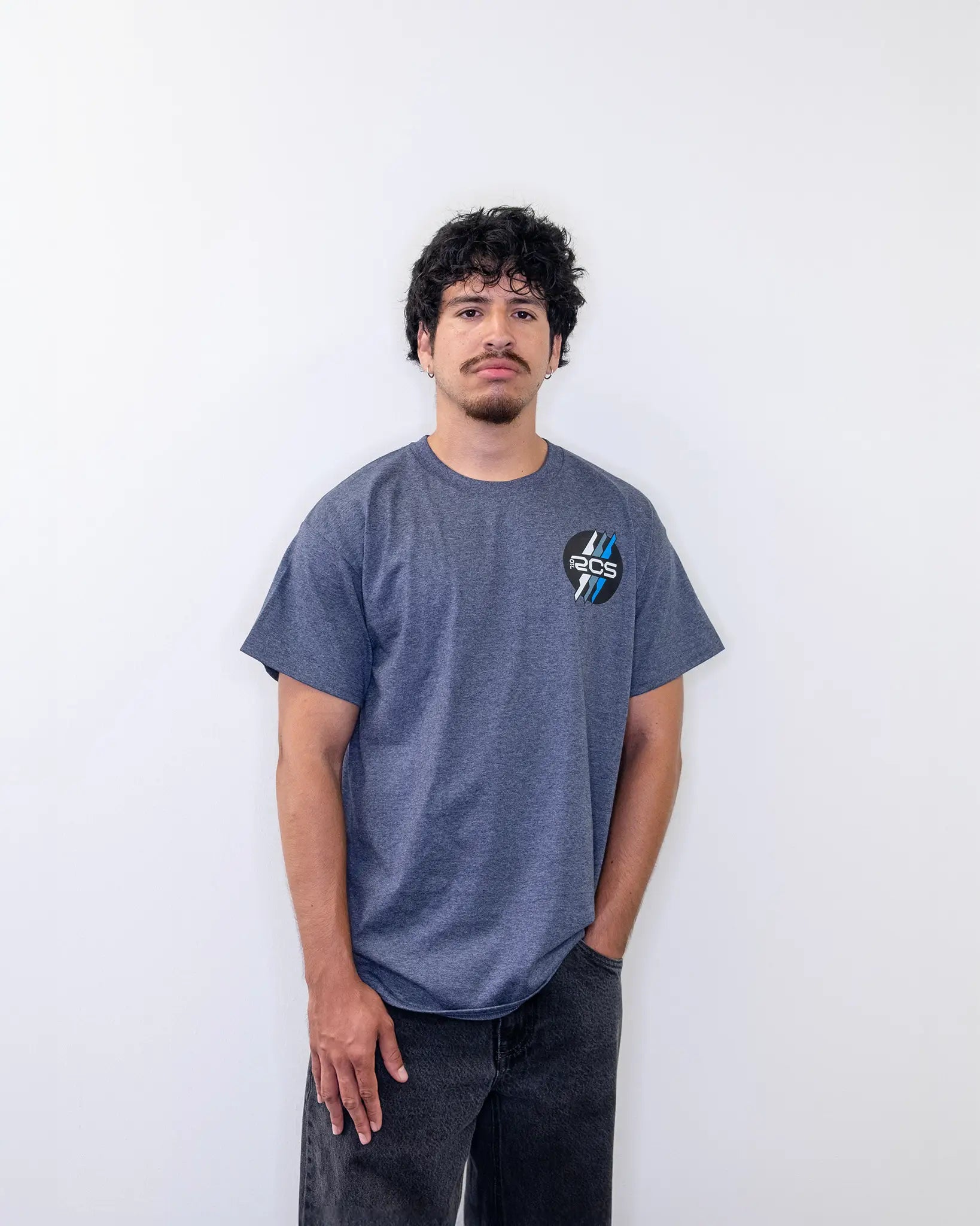 Model wearing a heather gray RCSTEVE 710 t-shirt featuring the RCS logo on the chest with blue and white stripes.